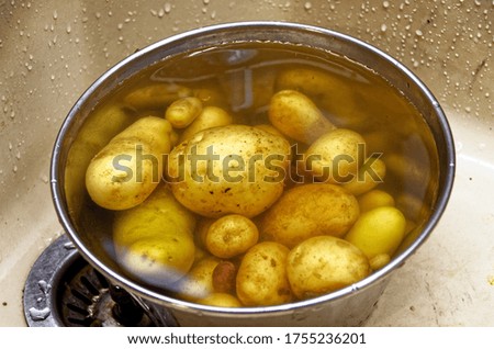 Detail of washing small potatoes in an iron bowl