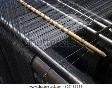 A detail of a weaving loom making wool cloth in a traditional textile mill.