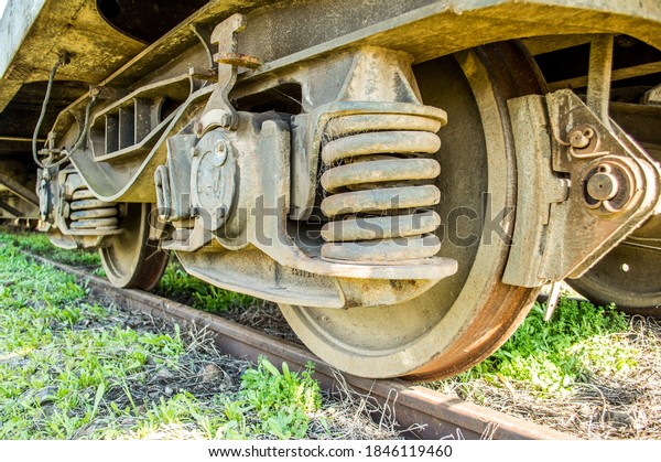 Detail of the wheels of an old\
rusty and broken train car, with spider webs and a lot of\
dirt
