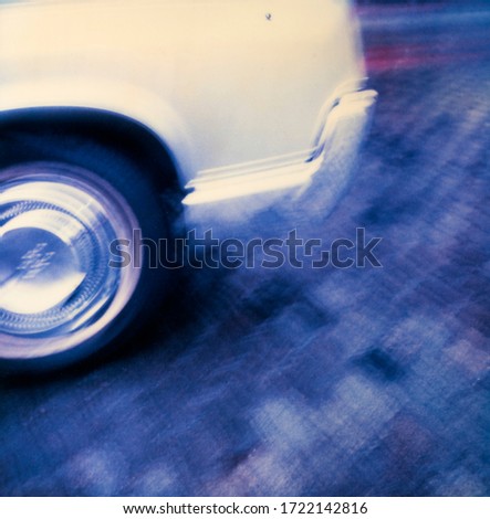 
detail of white automobile wheel and body in motion on bluish background