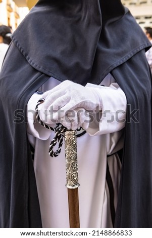 Detail of the white gloved hand of a Nazarene or penitent, holding a silver wand of command. selective focus with focus only on the hand of the Nazarene