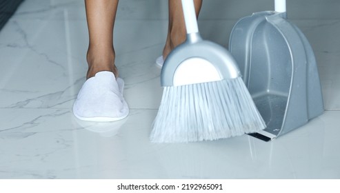 Detail of woman doing housework, holding a broom and sweeping floor.