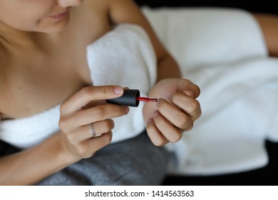 Detail of woman at home painting her nails after the shower.