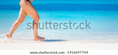 Detail of woman legs running on beach. Close-up of woman legs running on beach. Woman legs running, enjoying splashing beach aqua water, white sand, luxury summer vacation or holiday banner. 