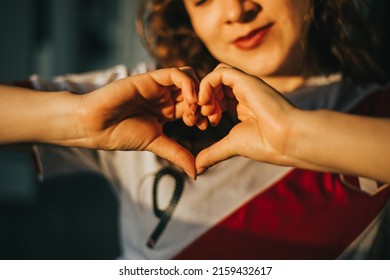 Detail of a woman making a heart with her hands while she is wearing a shirt from Peru. Sports concept.