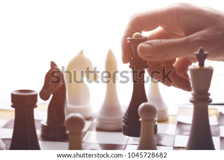 Detail of a woman's hand  in a chess game.
