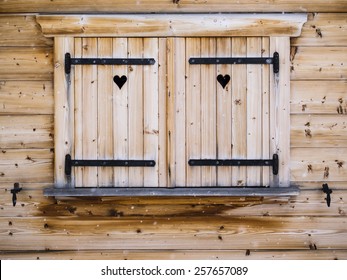 detail of wooden shutters on a rustic wooden cabin window with heart  shapes and falling snowflakes in foreground - Powered by Shutterstock