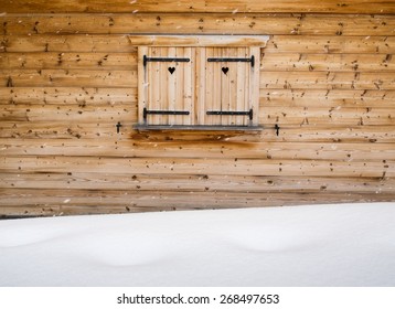 detail of wooden shutters on a rustic wooden cabin window with heart  shapes and falling snowflakes and snowdrift in foreground - Powered by Shutterstock