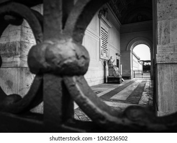 Detail Of A Wrought Iron Gate With Statue Of Pope Gregory XVI In The Background