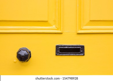 Detail Of A Yellow Front Door With Black Knob And Letter Box