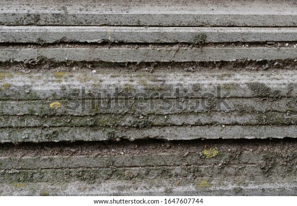 Detailed background of gray slate\
leaves. Outdated roofing material covered with moss and dirt. Side\
view. Eye level shooting. Close-up. Selective\
focus.