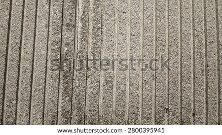 Detailed background texture of a linear concrete stone cladding panel, presenting a weathered grey surface with geometric striped parallel lines for contemporary building facades.