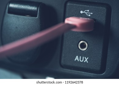 Detailed close up of a car usb port and auxiliary input with pink usb cable attached. - Shutterstock ID 1192642378
