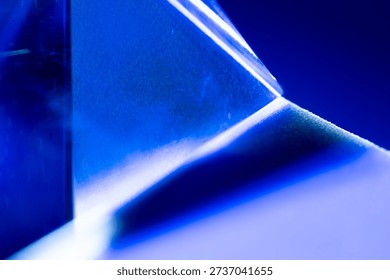 A detailed close up image capturing the tip of a translucent blue pyramid crystal against a deep blue background.