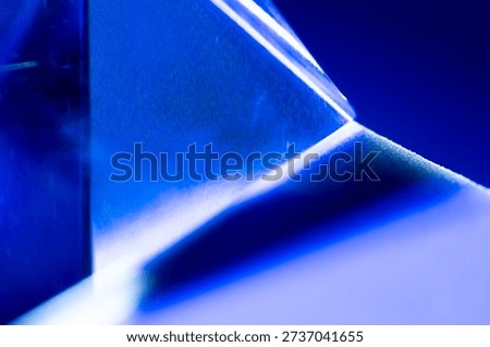 A detailed close up image capturing the tip of a translucent blue pyramid crystal against a deep blue background.