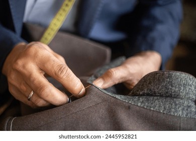 Detailed close up photo of an unrecognisable tailor hand stitching the under collar of a bespoke jacket - Powered by Shutterstock