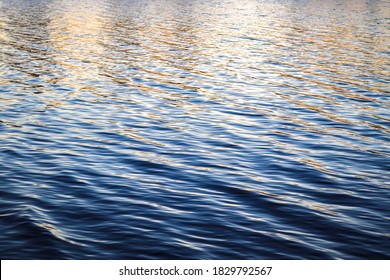 Detailed Close Up View On Water Surfaces With Waves And Ripples And The Sunset Sunlight Reflecting At The Surface