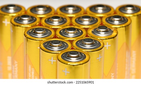 Detailed close-up of AA batteries isolated against a light background, arranged one behind the other in a triangle