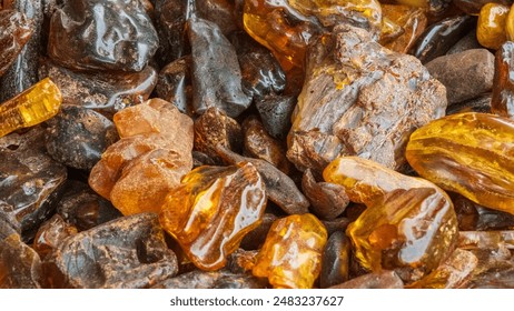 A detailed close-up of assorted polished and unpolished amber stones, showcasing their rich colors and textures. - Powered by Shutterstock