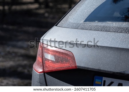 Detailed Close-Up of a Car's Rear Section with Dust Accumulation Reflecting Natural Light and a Subtle Elegant Design Highlighting the Vehicle's Tail Light Features and Shape