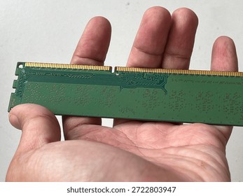 Detailed close-up of computer RAM memory modules with golden contact pins and green circuit board patterns. High-tech hardware components isolated on a neutral background, including a hand holding the module for scale. Perfect for technology upgrades, data storage, and digital infrastructure concepts.