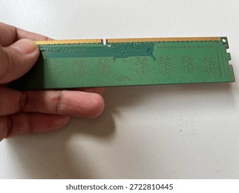 Detailed close-up of computer RAM memory modules featuring golden contact pins and green circuit board patterns. High-tech hardware components shown isolated and held by hand for scale. Perfect for technology upgrades, data storage, PC maintenance, and digital infrastructure concepts.