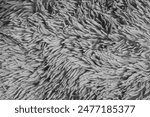 Detailed closeup of a fluffy grey carpet texture showcasing its soft and shaggy fibers with gorgeous glitter in a monochrome palette