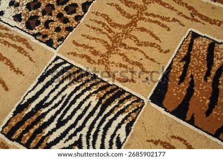 Detailed close-up of a patchwork carpet featuring various animal print patterns: tiger, leopard, and zebra. Luxury texture background for design and decor.