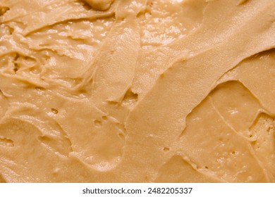 A detailed close-up of peanut butter in a swirl pattern, showcasing its smooth and creamy consistency - Powered by Shutterstock