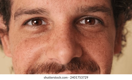 Detailed close-up shot of man's opening eye and looking at camera in studio on beige background - Powered by Shutterstock