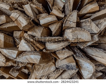 A detailed close-up shot of a stack of chopped firewood. The image highlights the organic texture, grain patterns, and rough edges of the cut wood, suitable for themes related to biomass, rustic home decor, energy, or natural textures