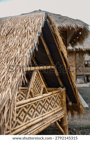 Detailed close-up shot of the triangular thatched roof and intricate woven bamboo wall of a traditional cottage.