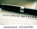 Detailed divorce settlement agreement form printed on paper, accompanied by a pen, signifies legal proceedings related to marital dissolution and negotiation between involved parties.