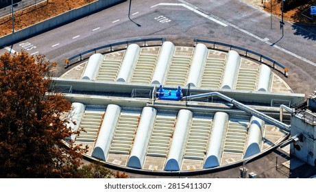 Detailed elevated view of a large covered circular process basin at an industrial water or wastewater treatment facility. Repeating curved roof sections form a distinctive radial pattern across the tank, while a central service bridge, metallic pipework, valves and mechanical equipment illustrate the technical complexity of modern treatment infrastructure.