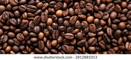 A detailed, high-resolution macro view of numerous roasted coffee beans, showcasing their rich brown colors and textured surfaces.
