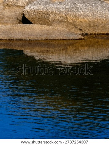 Detailed horizontal view of solid rock strata sharply contrasting with a rippling dark blue water surface.