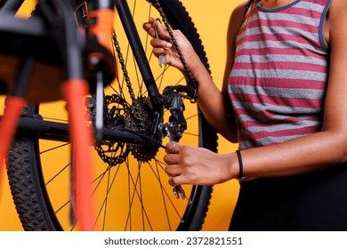 Detailed image of african american pair of hands expertly repairing bicycle wheel with a necessary work tool while doing maintenance. Black lady in close-up holding a wrench to tighten bicycle parts. - Powered by Shutterstock