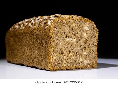 A detailed image of a freshly baked whole grain bread loaf topped with sunflower seeds, showcasing its texture, moisture, and rich wholesome appeal, isolated on a contrasting background.