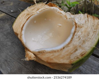 A detailed image of a halved coconut showcasing fresh coconut water and fleshy interior. Set against a rustic wooden background, highlighting the natural texture and freshness. - Powered by Shutterstock