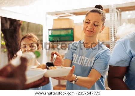 Detailed image showcasing female caucasian charity worker serving warm meal to underprivileged african american person. Woman volunteer handing out free food to the hungry and needy homeless people.