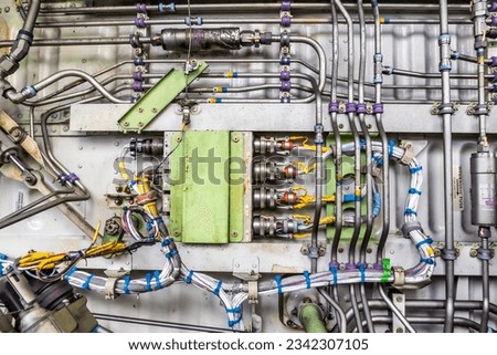 Detailed image of various pipes, hoses, tubes from the inside of an airplane. Hydraulic lines, valves, tubes, switches and wires in colourful arrangement.