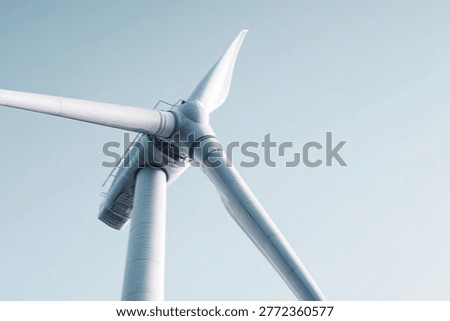 A detailed, low-angle view of a single wind turbine blade and hub, highlighting its sleek design against a gradient blue sky.