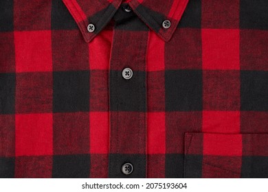 Detailed photograph of a men's flannel shirt in a tartan pattern, showing a portion of the collar and pocket with the centerline and buttons