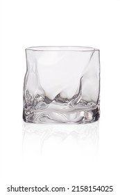 Detailed shot of a glass in the form of a spherical ice. The designer transparent asymmetrical glass with a thick bottom is isolated on the white background.