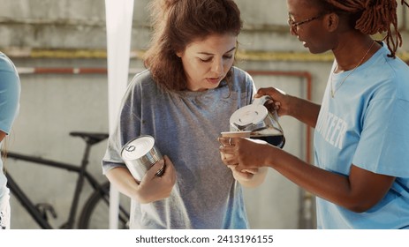 Detailed view of african american female volunteer serving a cup of coffee to homeless caucasian lady. Friendly black woman at outdoor food bank sharing nourishments to the needy and less fortunate. - Powered by Shutterstock