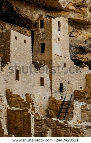 A detailed view of centuries-old Pueblo architecture, showcasing the intricate stonework nestled in a cliff face