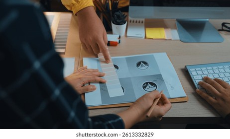 A detailed view of a collaborative design session in a modern office. Hands engage with sketches and color palettes, illustrating creativity and teamwork in a workspace. SACTR