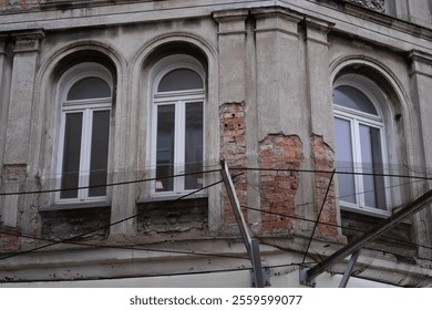 A detailed view of a crumbling building facade with exposed red bricks and worn down plaster in Wroclaw.  - Powered by Shutterstock