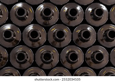 Detailed view of dark glass bottle openings arranged in rows showing industrial manufacturing precision. Quality control in olive oil bottling process. - Powered by Shutterstock