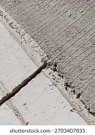 Detailed view of the junction between three rough concrete blocks. The upper right block has distinctive diagonal scratch marks..